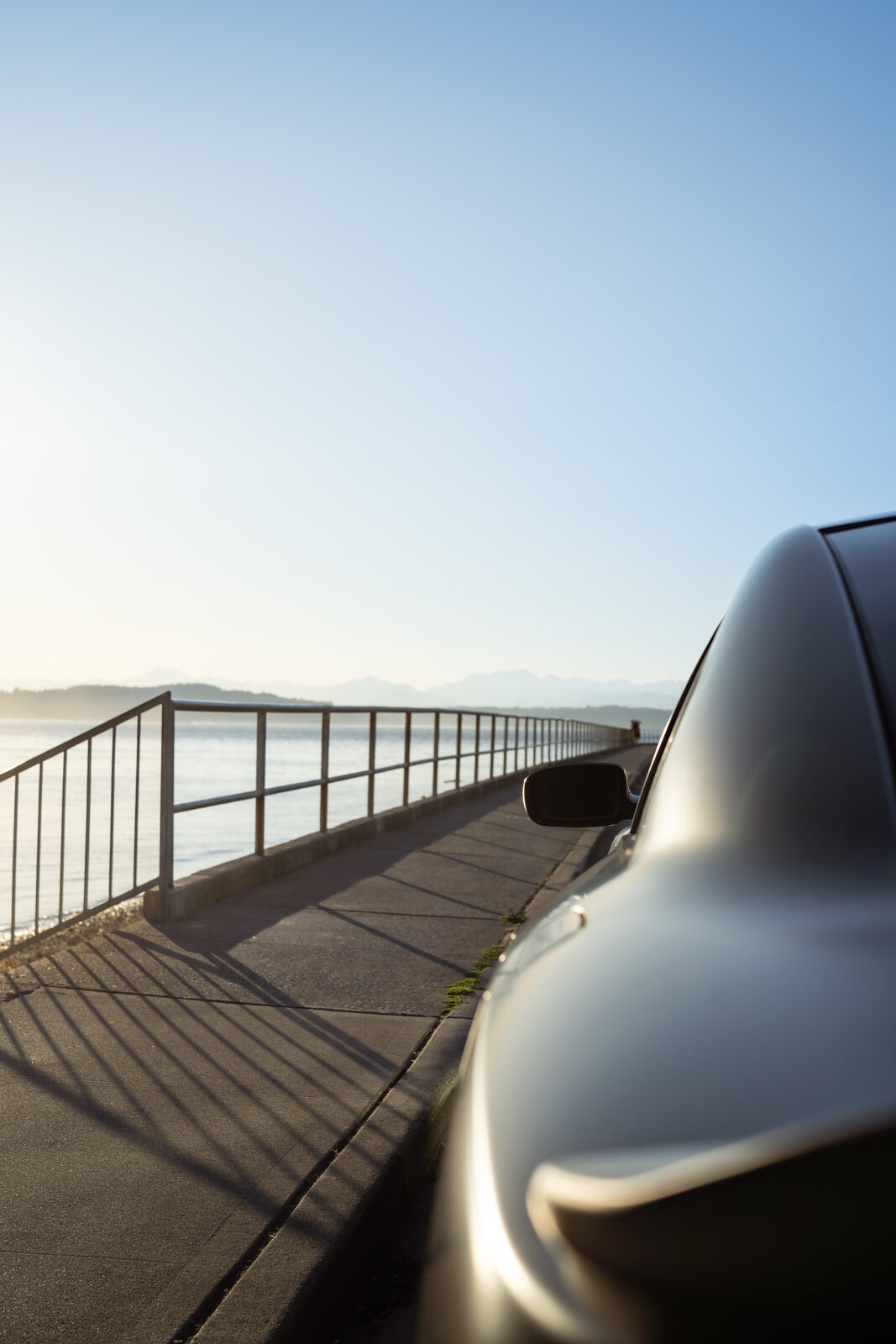 Low evening sun over Puget Sound beside a car parked at a waterfront railing